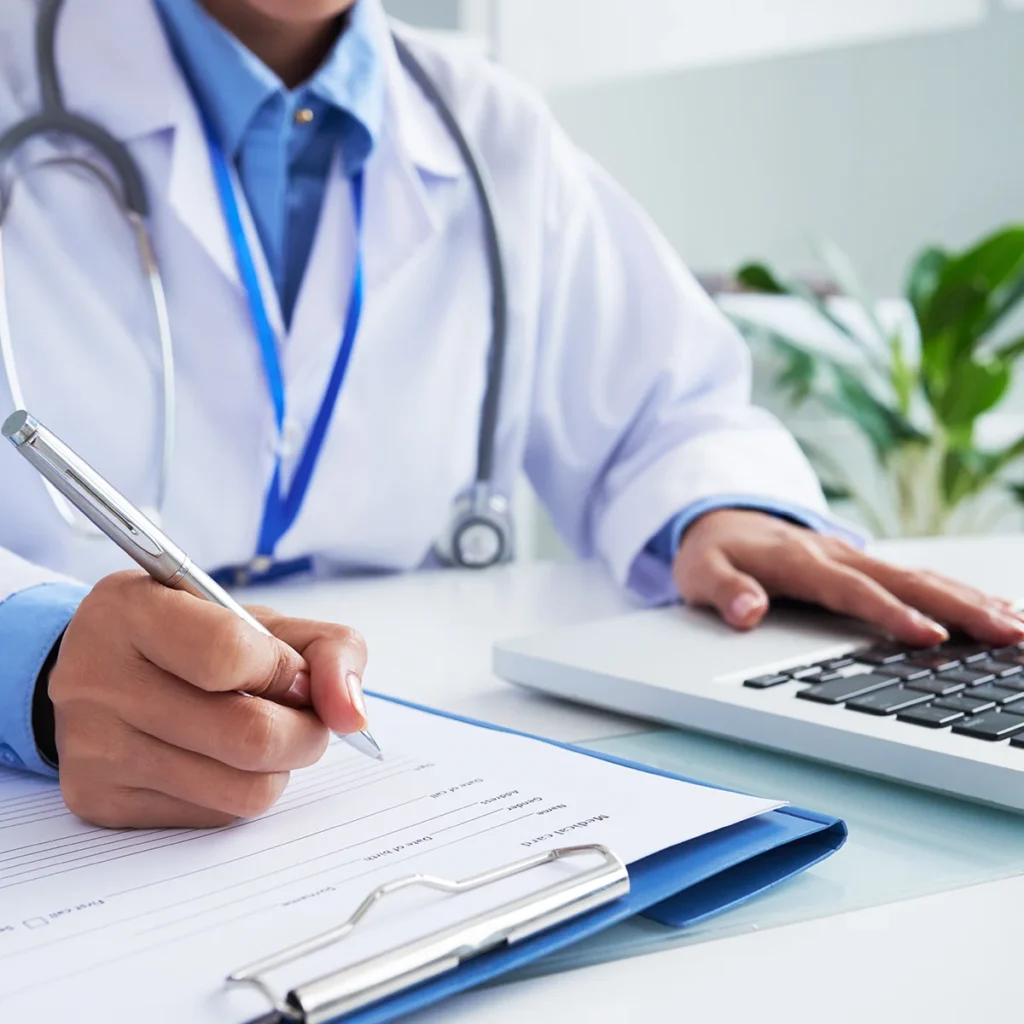 Médecin qui utilise un ordinateur et qui prend des notes